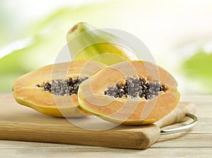 Whole and halved papayas on a wooden board