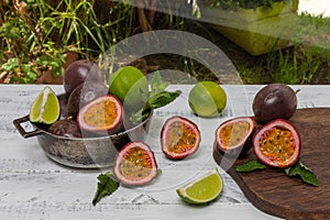 Whole and halved passion fruit or gulupa next to lemons and spearmint