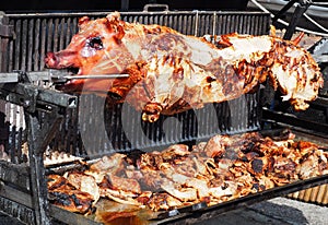 Whole large pig on rotary spit grill, with the slices of meat cut flat during cooking