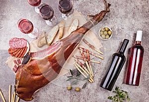 Whole leg HAM JAMON SERRANO and red and rose wine on gray background. Top view. Flat lay photo