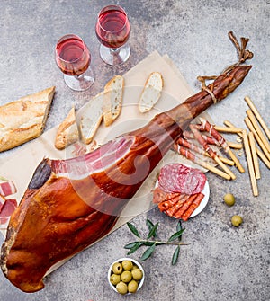 Whole leg HAM JAMON SERRANO and rose wine on gray background. Top view. Flat lay