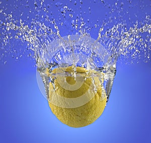A whole lemon splashing into water