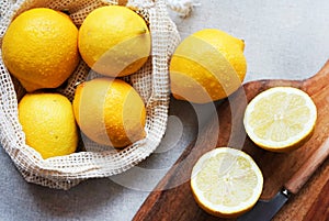 Whole lemons next to cut ones on a wooden board next to a knife