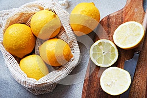 Whole lemons next to cut ones on a wooden board next to a knife