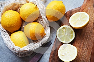 Whole lemons next to cut ones on a wooden board next to a knife