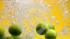 Whole limes falling into water