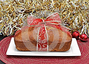 Whole loaf cake wrapped in a red and gold ribbon.