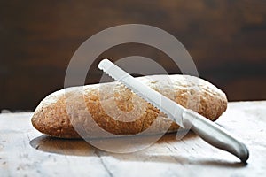 Whole loaf homemade bread knife wooden table close up