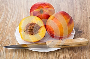 Whole nectarines, half of nectarine and knife in plate