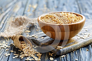 Whole oats in a bowl and oat flakes in a wooden scoop.