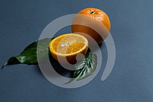 A whole orange and half an orange, and two green leaves