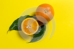 A whole orange and half an orange, and two green leaves