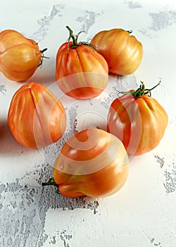 Whole organic tomatoes Coeur De Boeuf. Beefsteak tomato on white rustic table