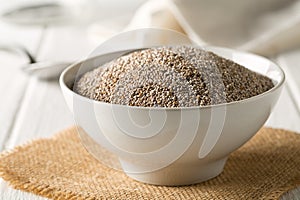 Whole, organic white chia seeds heap in white bowl with bright kitchen background