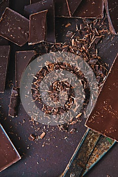 Whole and pieces of dark chocolate bars on a darkbackground at