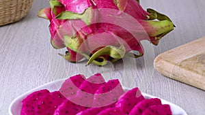 Whole and pieces fresh red dragon fruit, pitahaya close up at a plate