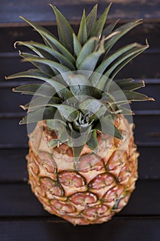 Whole pineapple fruit positioned on a wooden table