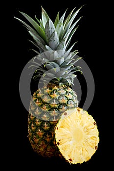 Whole pineapple isolated standing on black.