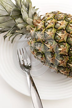 Whole pineapple on a plate on a white background. Tasty and healthy vegetarian food