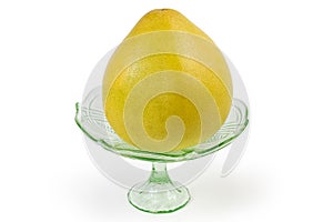Whole pomelo in glass fruit vase on a white background