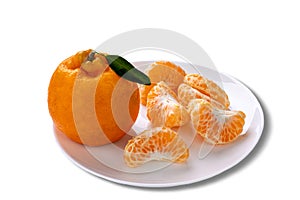 Whole Ponkan tangerine and one peeled in segments on a plate isolated on white background photo