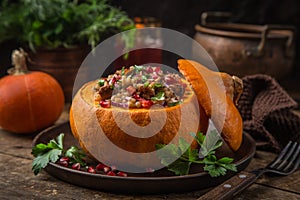 Whole pumpkin stuffed with barley and vegetables, served with pomegranate and parsley