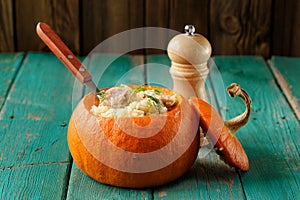 Whole pumpkin stuffed with rice and meat on turquoise table