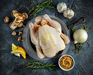 Whole Raw Chicken in iron pan, with ingredients for cooking. on stone background