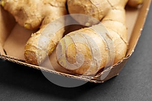 Whole raw ginger root or rhizome in paper packaging on a black background close up