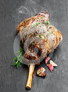 Whole roast lamb leg on black stone background