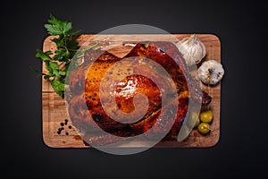 Whole roasted chicken on cutting board with vegetables over black background