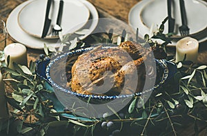 Whole roasted chicken decorated with olive tree branch, selective focus