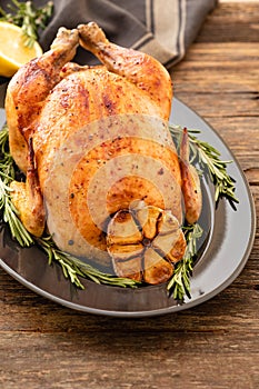 Whole roasted chicken with lemon and rosemary on a black plate. Rustic style. Christmas concept. Christmas turkey.