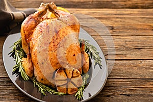 Whole roasted chicken with lemon and rosemary on a black plate. Rustic style. Christmas concept. Christmas turkey.