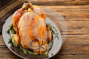 Whole roasted chicken with lemon and rosemary on a black plate. Rustic style. Christmas concept. Christmas turkey. Top