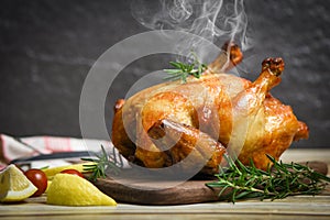 Whole roasted chicken rosemary and tomato lemon on wooden cutting board - Baked chicken grilled barbecue delicious food on dining