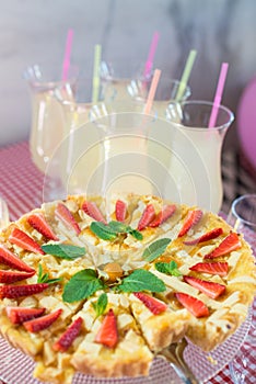 Whole round apple pie decorated with strawberry on a glass stand
