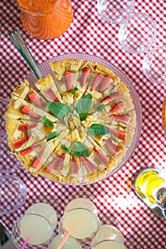 Whole round apple pie decorated with strawberry on a glass stand