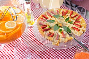 Whole round apple pie decorated with strawberry on a glass stand