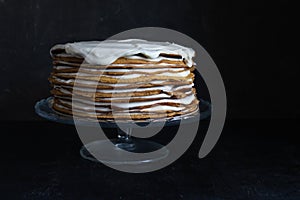a whole round honey cake on a stand against a dark background