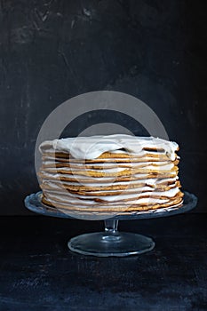 a whole round honey cake on a stand against a dark background