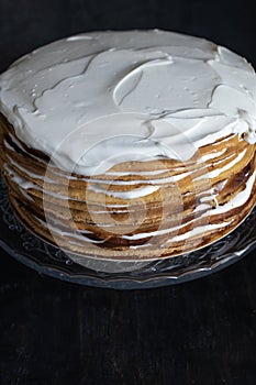 a whole round honey cake on a stand against a dark background