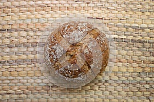 Whole rye bread placed on traditional wickerwork texture.