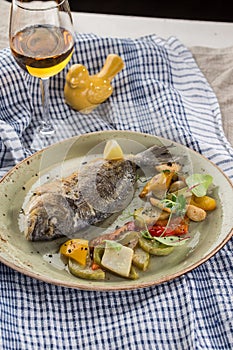 Whole seabass fish grilled with vegetables, herbs and glass of white wine