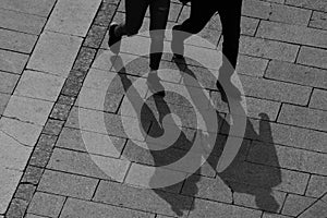 The whole shadow of a man and woman on a stone walkway is in the foreground.