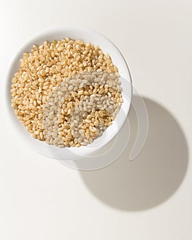 Whole Short Grain Rice Seed. Grains in a bowl. Shadow over white photo