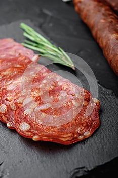 Whole and sliced chorizo sausage on black background