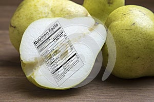 Whole and sliced green pears with nutrtional label on wooden boa