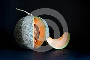 Whole and sliced Japanese melons, honey melon or cantaloupe on black isolated background, copy space. Summer fruits.