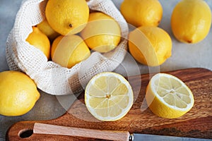 Whole and sliced lemons on a wooden board next to a knife